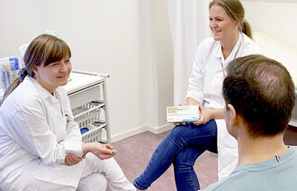 Bildet viser en pasient i konsultasjon hos lege og sykepleier