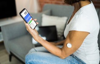 Bildet viser en kvinnelig pasient som bruker CGM (kontinuerlig glukosemåling) for å måle blodsukkeret. Verdiene sendes via bluetooth til mobilen.