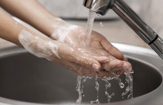 En person vasker hendene i rennende vann