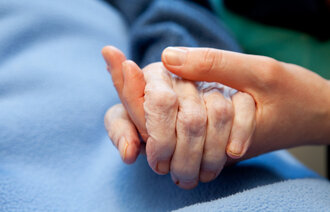 En sykepleier holder hånden til en pasient