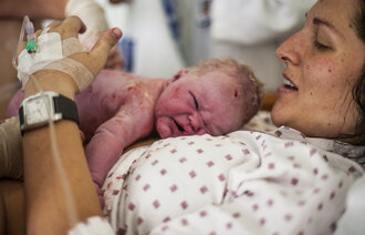 Bildet viser en nyfødt baby som ligger på magen til moren