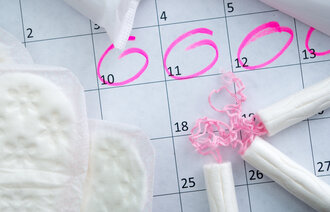 Kalender med tamponger og bind. Illustrere menstruasjonssyklus.