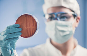 Bildet viser en forsker som holder en petriskål.
