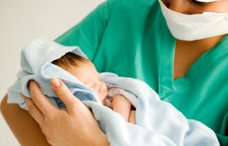 Bildet viser en jordmor som holder et nyfødt barn.