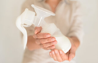 Bildet viser en kvinne som gir fra seg en flaske med morsmelk