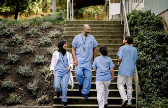 Bildet viser fire helsepersonell som går i en trapp ute