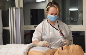 Bildet viser sykepleierstudent Lisa Lervåg som øver på å legge inn sentralt venekateter
