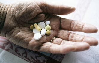 Bildet er et nærbilde av en hånd som holder ulike piller.