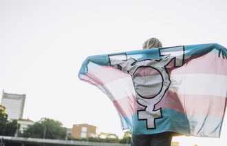 Bildet viser en person som holder opp et flagg med kjønnssymboler