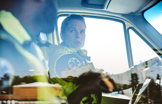 Bildet viser to ambulansearbeidere som sitter i en bil