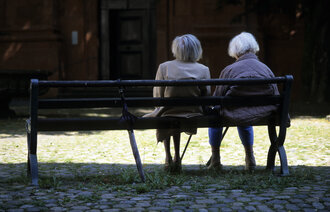 Bildet viser to eldre kvinner som sitter på en benk
