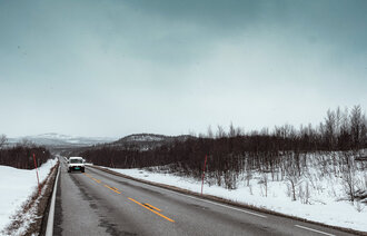 Bildet viser en bil alene på veien i Karasjok