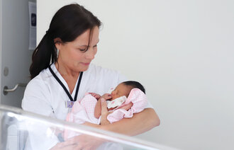 Bildet viser Kariann Turøy Bakstad med en nyfødt baby på armen