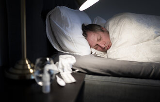 Bildet viser en forkjølet mann som ligger i sengen