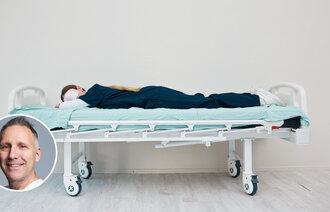 Bildet viser en sliten sykepleier som har lagt seg på en trilleseng på sykehuset