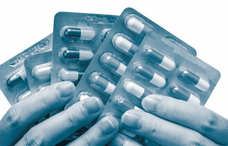 Bildet viser to hender som holder flere brett med piller