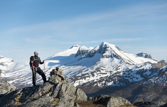 Bildet viser en mannlig turgåer som står på en fjelltopp