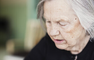 Bildet viser en tankefull eldre kvinne