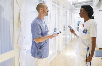 Bildet viser to sykepleiere som snakker sammen