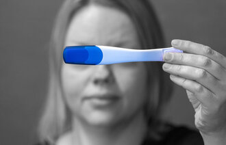 Bildet viser en kvinne som holder opp en graviditetstest.