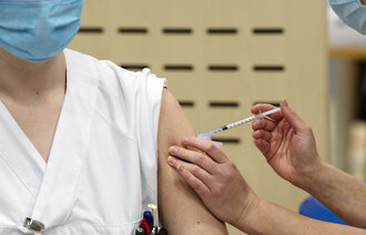 Bildet viser en sykepleier som gir koronavaksine