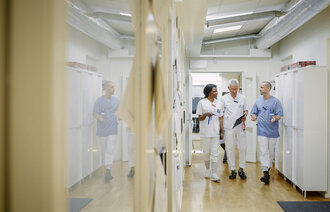 Bildet viser tre helsearbeidere som går og diskuterer