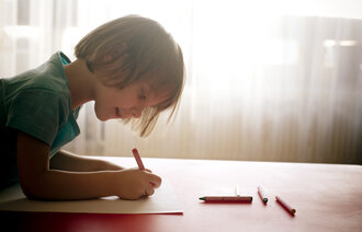 Bildet viser en jente på fire år som tegner i barnehagen