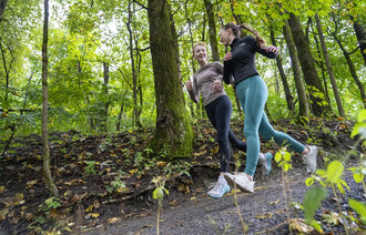 Bildet viser to unge kvinner som jogger i skogen.