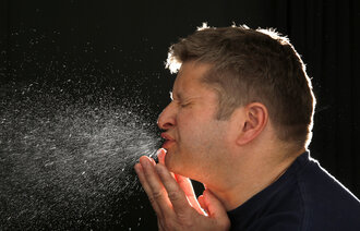 Bildet viser en mann som nyser