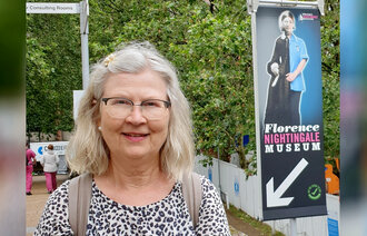 Bildet viser innleggsforfatter Ingeborg Nilsen som står foran en banner med bilde av Florence Nightingale