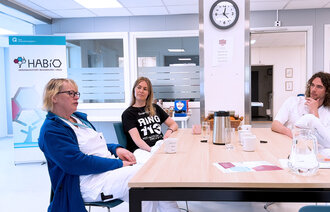 Bilde viser tre sykepleiere som sitter ved et bord på HABiO