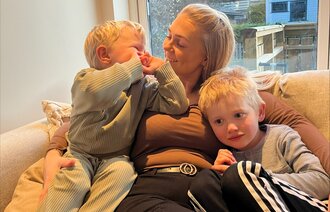 Bildet viser Erika Rosenvinge i sofaen sammen med sine to barn