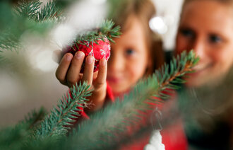 Bildet viser en liten jente og hennes mor som pynter juletre