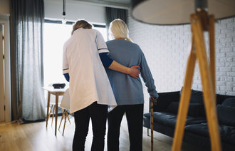 Pleier og eldre Bildet viser en pleier som støtter en eldre pasient