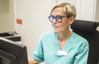 Bilder viser en sykepleier som skriver på en PC