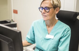 Bilder viser en sykepleier som skriver på en PC