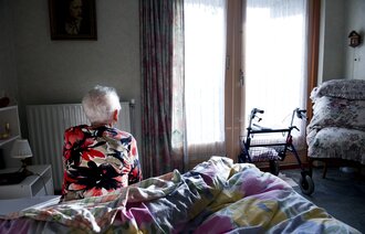 Bilde av eldre person på sengekanten på soverommet