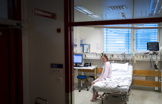 Bildet viser en pasient som sitter i en sykehusseng Bildet viser en pasient som sitter i en sykehusseng