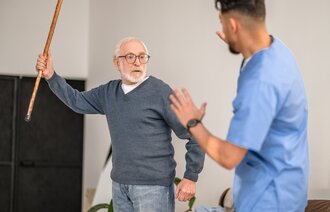 Bildet viser en aggressiv pasient som prøver å slå en sykepleier