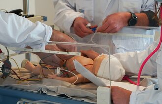 Bildet viser masterstudenter i barnesykepleie som simulerer på en dukke