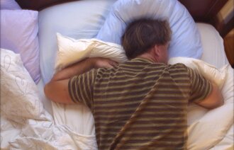 Bildet viser en mann som sover på magen.