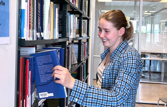 Bildet viser innleggsforfatteren som tar en bok ut av en bokhylle