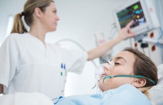 Bildet viser en sykepleier som pleier en pasient i sengen