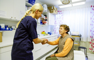 Bildet viser en sykepleier som er med en pasient Bildet viser en sykepleier som er med en pasient.