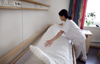 Bilde av helsearbeider som rer opp seng