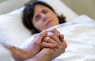 Bilde av sykepleier som holder pasient i hendene