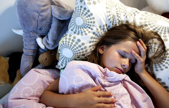 Bildet viser en ung jente som ligger i senga