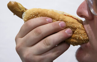 Bildet viser en mann som spiser en pølse i brød.