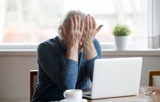 Bildet viser en eldre dame som er sliten foran en datamaskin