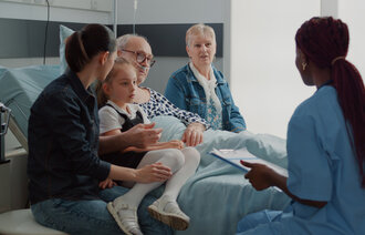 Bildet viser pasient med pårørende som snakker med en sykepleier
